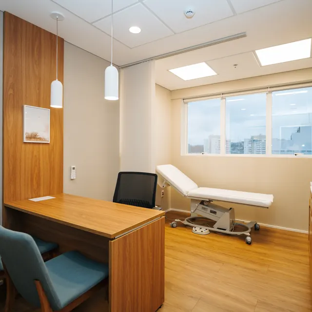 Sala de atendimento do consultório, com mesa e maca